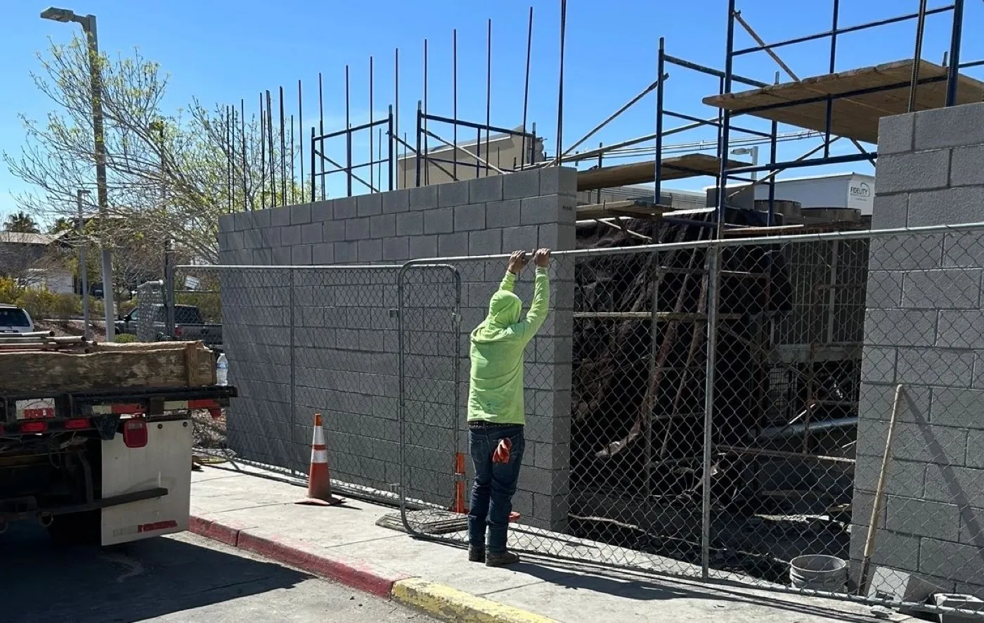 Precision block screen wall going up around rooftop equipment on a Las Vegas commercial lot, rebar standing above the top course