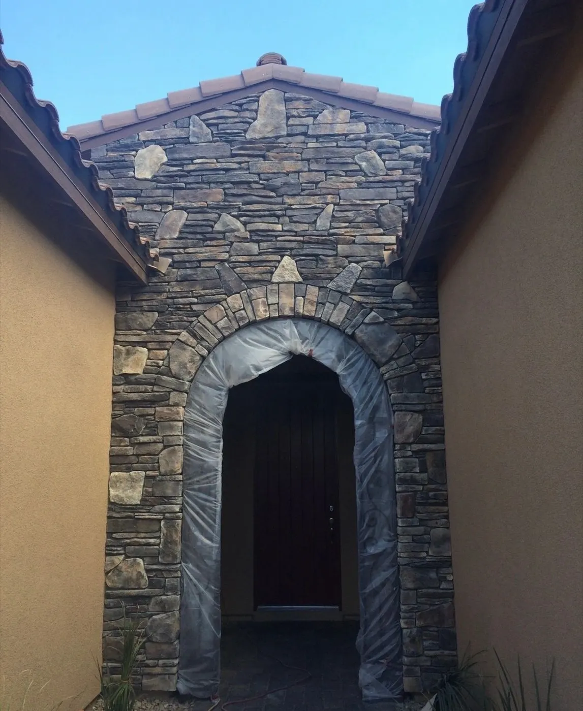 Stone veneer entry gable and arched doorway on a stucco home in Las Vegas