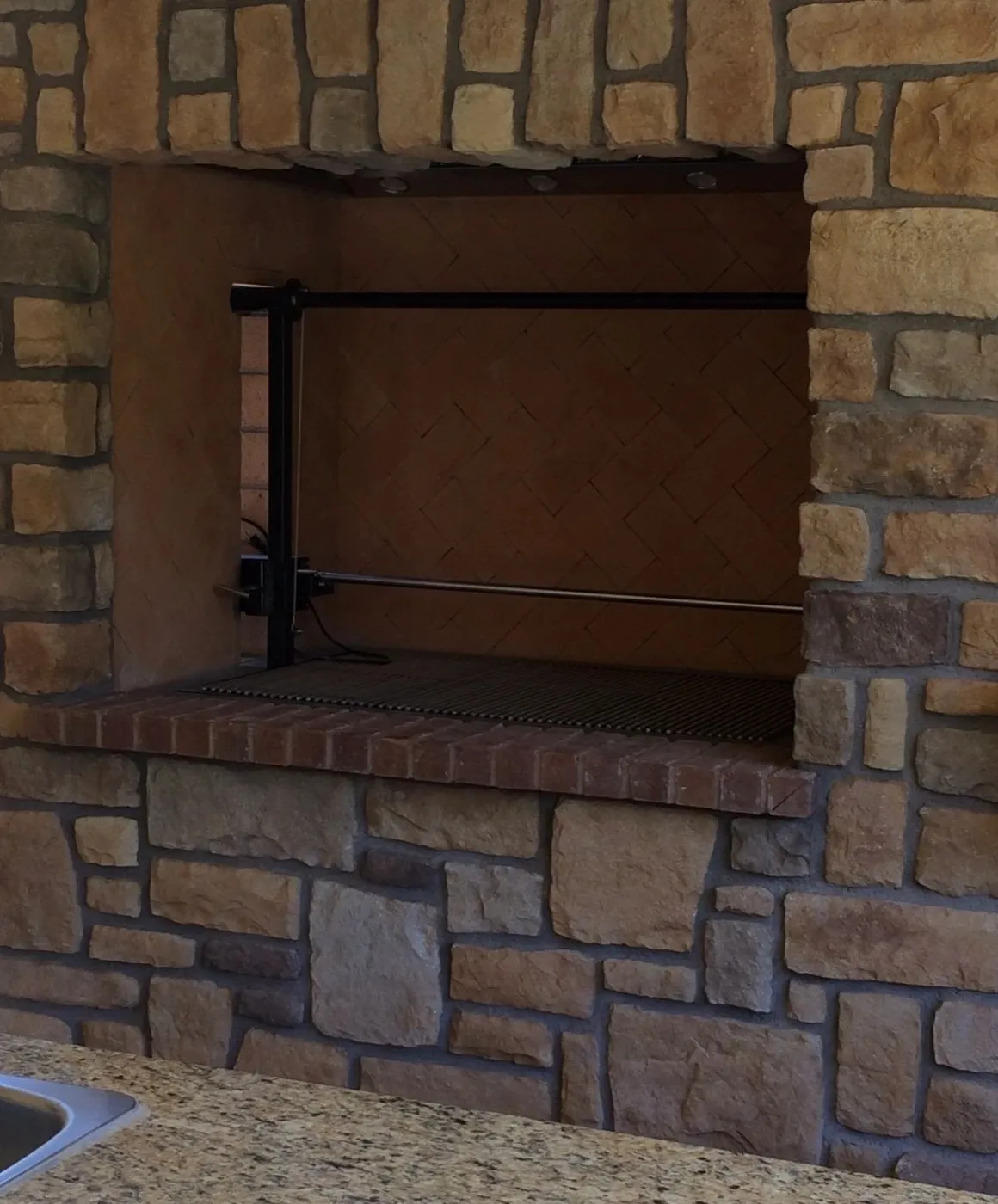 Stone veneer fireplace face with a brick ledge around the firebox opening